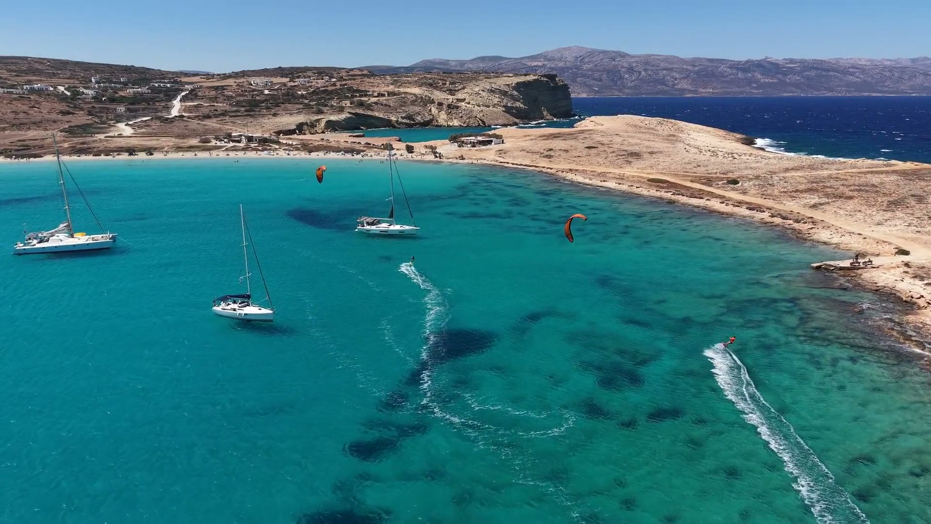 Sailboats and kitesurfers in a turquoise bay on our trip to Greece